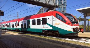A red, green, and white Fiumicino Airport Leonardo Express train arriving at the platform