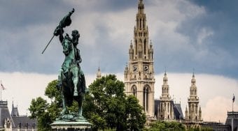 A view of a historic church in Vienna with a large horseman statue in front.