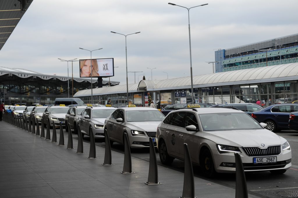 A side view of white airport taxis lined up at the taxi rank outside of the terminal.