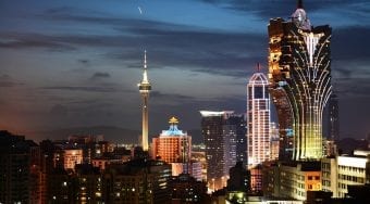 Tall buildings in Macau city center lit up at night.