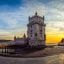 View of the Belem Tower in Lisbon, with blue water in the background and cloudy sunset skies above.