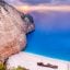 Scenic view of Navagio Beach at sunset, with dramatic white cliffs, turquoise waters, and the famous shipwreck on the sand—an iconic stop often included in a transfer from Zakynthos Airport to the island’s top attractions.