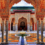 Moroccan architectural structure with pillars and gilded walls surrounding a fountain.