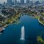 A boat leaving a trail as it travels up a lake surrounded by greenery and city buildings