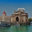 A waterfront view of The Gateway to India with a ferry approaching