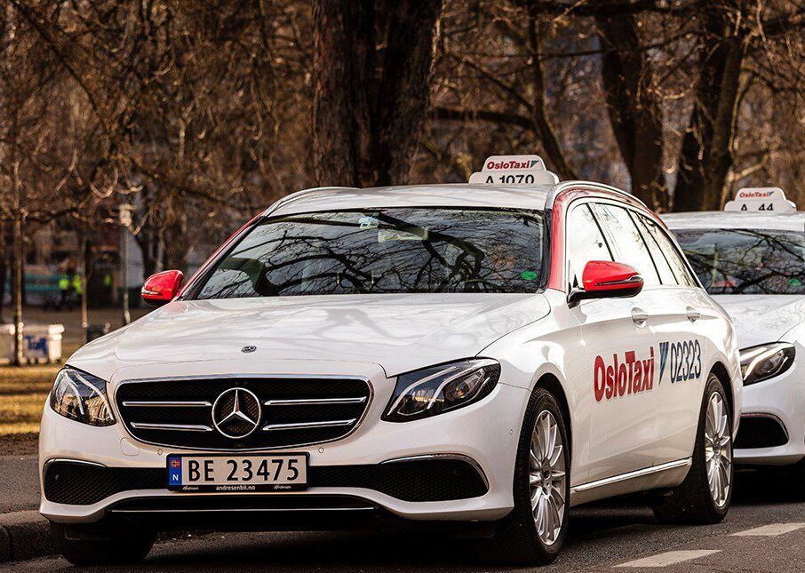 Oslo taxi white car with taxi sign on roof and big red sign on the door reading