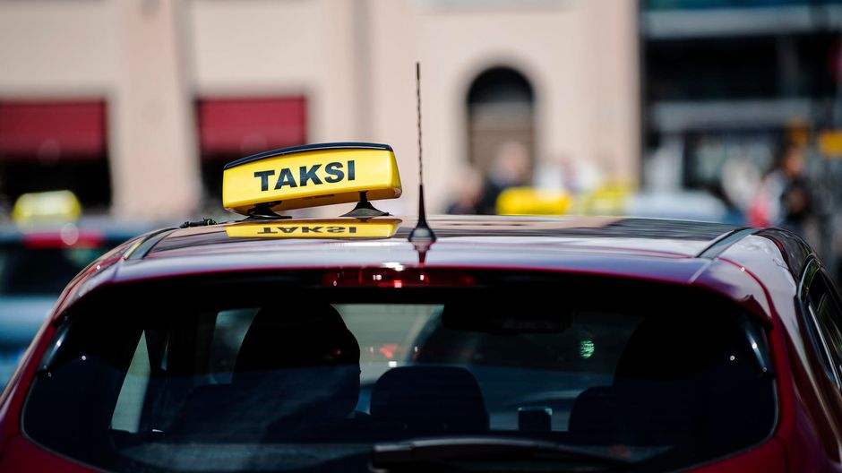 yello taxi sign on top of red cab in helsinki finland