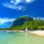 clear blue waters and a sandy beach with jungle appearing in distance