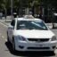 taxi in Adelaide represented in a white vehicle with a taxi signage on top, driving on the road