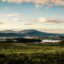landscape view of nature, green field with mountain peaks in distance on a cloudy day