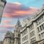 older city buildigns and religious building photogrpahed under a pink, blue and purple sky