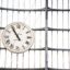 clock showing the time photographed in front of glass building during daytime