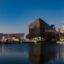 City buildings and the cathedral near a body of water in Liverpool city center. Take a taxi from Liverpool airport to Liverpool city center and start exploring