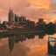 body of water near city buildings under a stunning orange cloudy sky during sunset