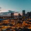 Nashville skyline filled with tall buildings with the sun setting in the background giving a stunning colour to the sky as blue grey yellow orange and pink mix