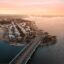 aerial view of city buildings and freeway near body of water in daytime