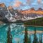 snowy mountain peaks at distance reflecting on milky turquoise body of water near dark green fir trees