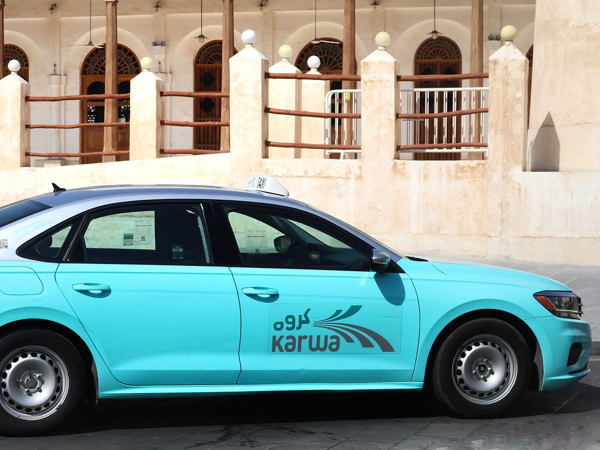 Doha, Qatar taxi neon blue coloured taxi with white and black taxi sign on the roof in front of concrete building