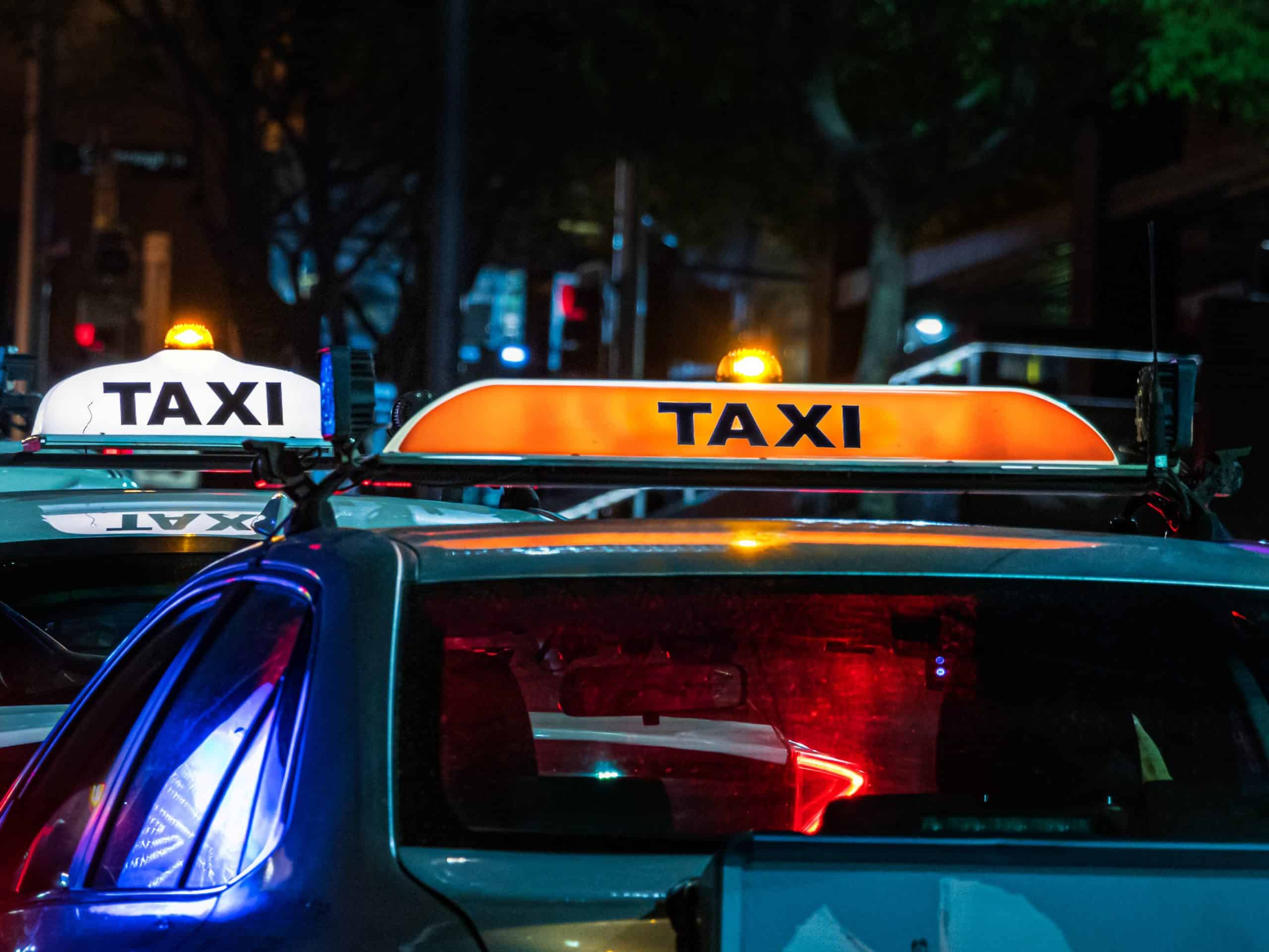 two taxis photographed at night with signature sign on roof