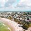 Aerial View of Kings Beach on the Sunshine Coast, Queensland showing blue green waters, plenty of people enjoyign themselves, houses and hotels