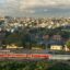railway with trains in front of an array of houses under a cloudy sky