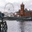 wooden bollard in front of The Giant Wheel and Pierhead at Cardiff Bay, Wales on a cloudy day