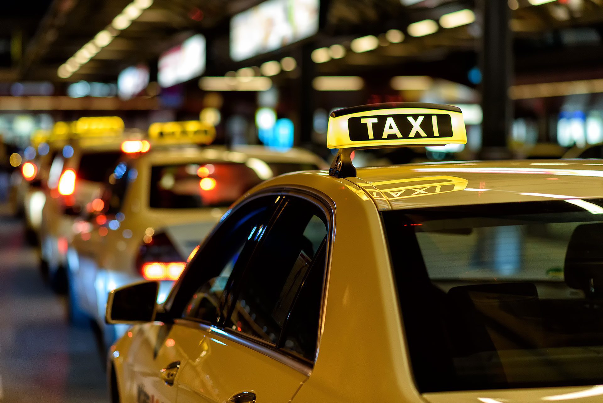 yellow taxis lining up at cab rank, with lighted taxi sign on roof