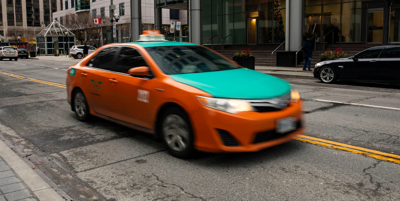 blurred in-movement orange and turquoise taxi vehicle driving