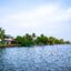 island with a colourful home and green trees surrounded by blue waters and a blue sky in daytime in Alleppey, India