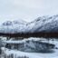 snow covered mountain near a mostly frozen body of water in daytime