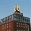 red brick building with small windows and a lighted letter U on the roof in Dortmund under a clear day sky