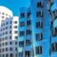 contemporary white and blue buildings with lots of windows under a blue day sky