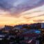aerial view of city buildings by the sea and lights at golden hour