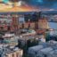 An aerial photo at golden hour of white, light green and brick red city buildings by a body of water in Hamburg.