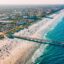 aerial view of coastline, a busy sandy beach, blue waters and the city from a distance