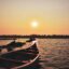 sunset photo of red/brown boat in the sea