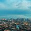 aerial view of Manila city buildings and body of water running through town, under a blue day sky