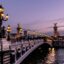 parisian bridge with lights over body of water after golden hour