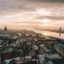 Aerial view of Riga city buildings near water on a cloudy day, with easy access to Riga airport taxi services.