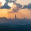 sun setting over Taipei's city skyline with mountain silhouettes in the front