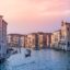 landscape image of Venice canal with a boat in the middle under a pink sky