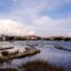 blue water and rocky formations with city buildings and trees at distance under a cloudy sky in daytime in Zadar
