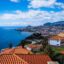 aerial shot of city houses by the blue sea under a cloudy sky in daytime in Madeira, Funchal - Portugal