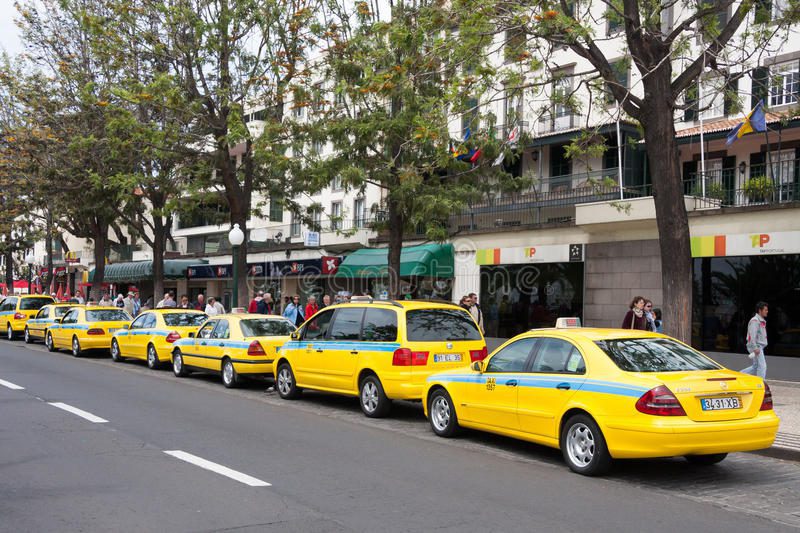 taxis lining up by the pavement on a busy road