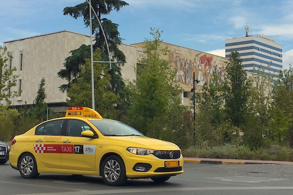 tirana taxi Yellow taxi roaming the street with a signature sign on the roof and 'taxi' sticker on the side
