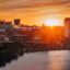 sun setting over the city buildings that are located near a body of water