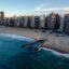 coastline with a wavy sea near a row of high rise city buildings in Fortaleza, Brasil