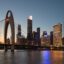 lighted buildings and bridge over body of water after sunset
