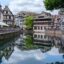 buildings and flowers reflect onto body of water in Strasbourg, France.
