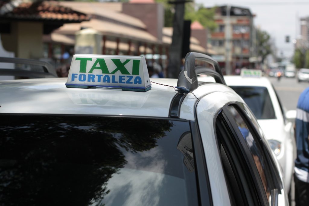 Fortaleza Taxi white taxi vehicles on the street with a signature roof sign that states taxi in green and fortaleza in blue capital letters